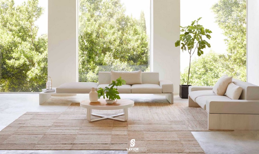 Phòng khách sử dụng nội thất làm từ vật liệu tự nhiên (gỗ, đá, thảm đay) để bổ sung cho một bức tranh toàn cảnh rợp bóng cây. 